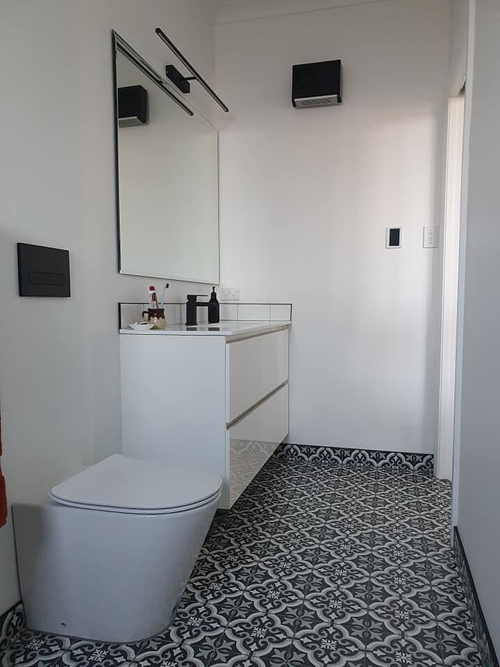 Guest bathroom with patterned floor tiles and a wall-hung vanity